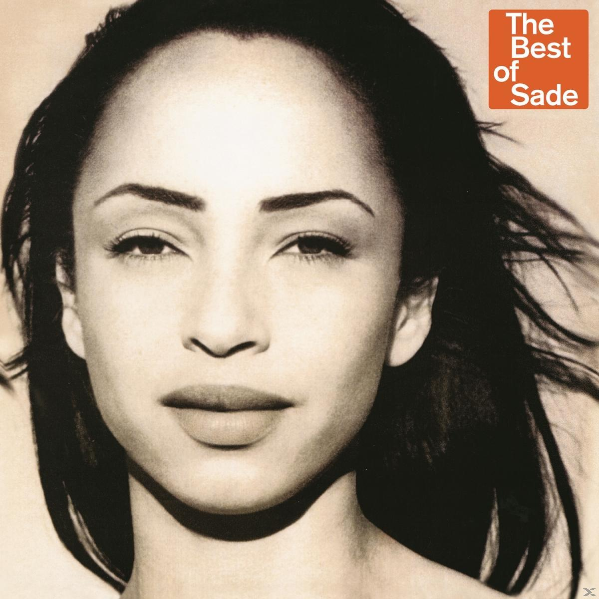 Gros plan d'une femme aux cheveux noirs, regardant la caméra. Boîte rouge avec 'The Best of Sade'.