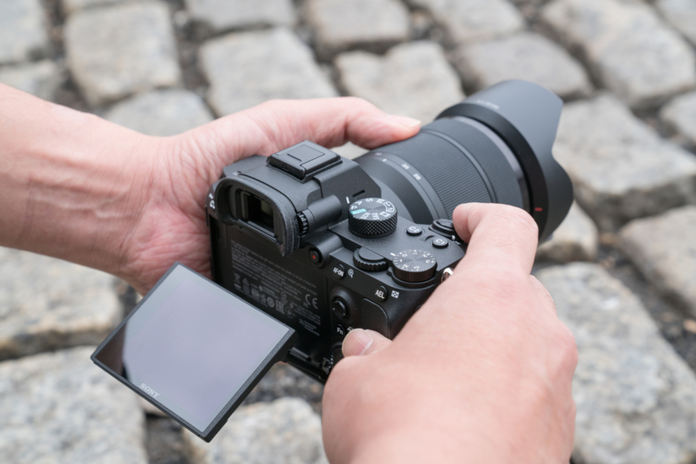 A person holding a camera, with a screen turned out.