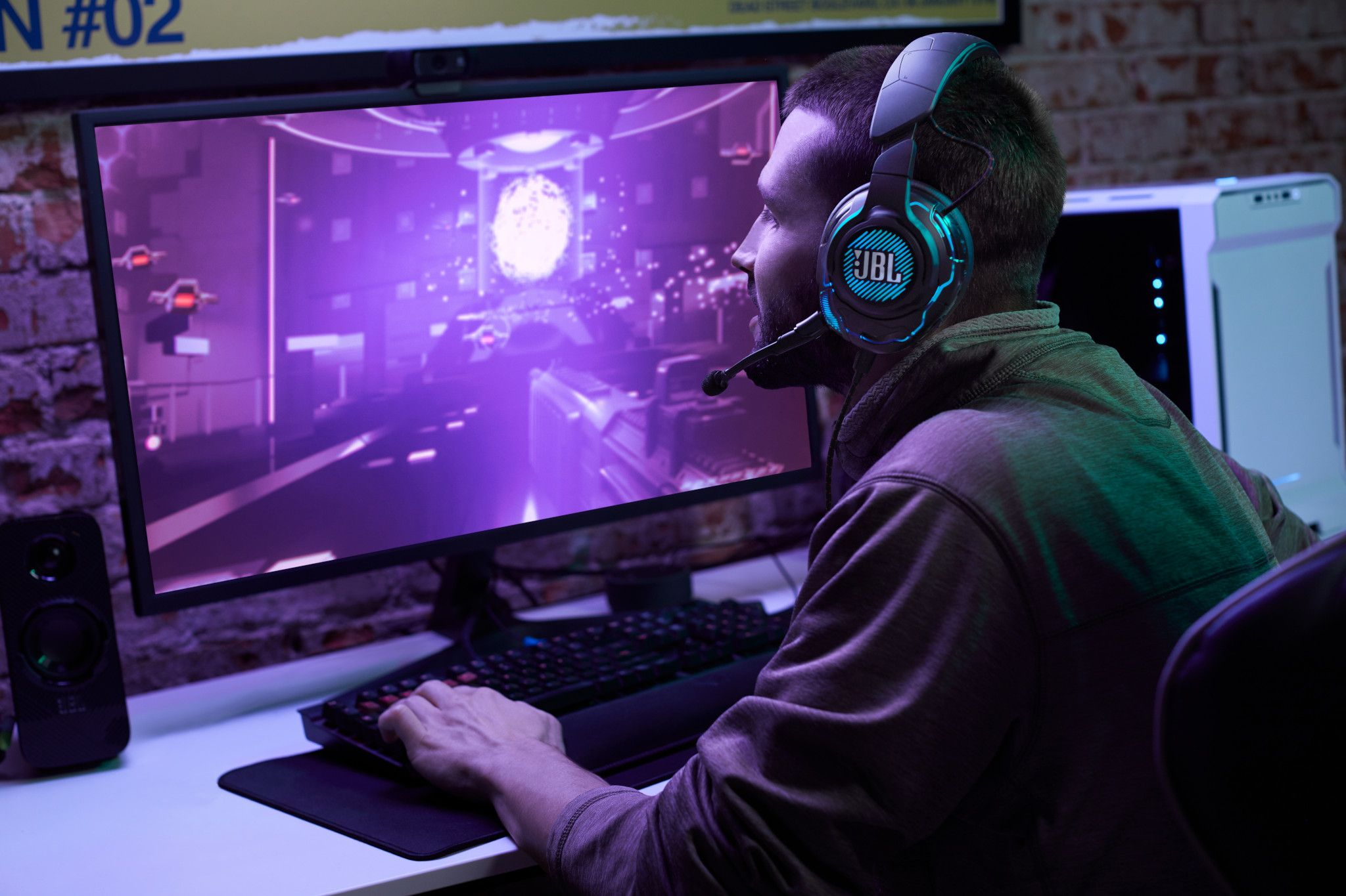 Een gamer die een headset en toetsenbord gebruikt voor een monitor met een levendige gamescène.