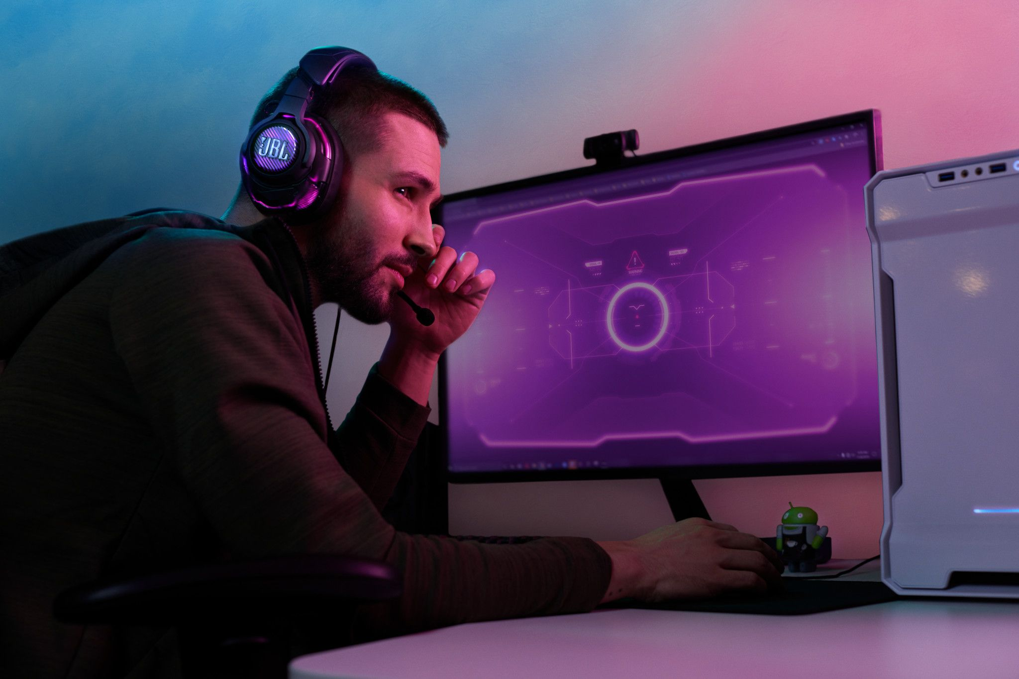 Een man is aan het gamen, draagt een headset en kijkt naar een monitor met een game-interface.
