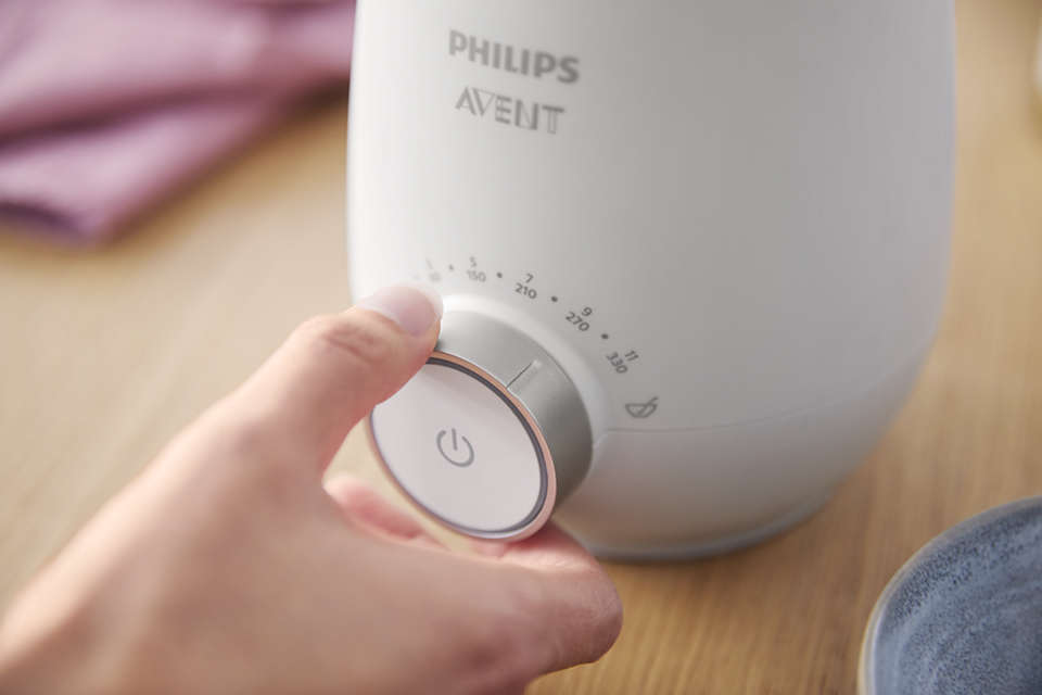 Eine Hand dreht einen Knopf an einem weißen Philips Avent Gerät mit Temperatureinstellungen.