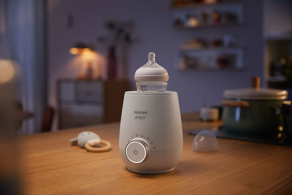 Ein weißer Philips Avent Flaschenwärmer mit Flasche auf einem Holztisch.