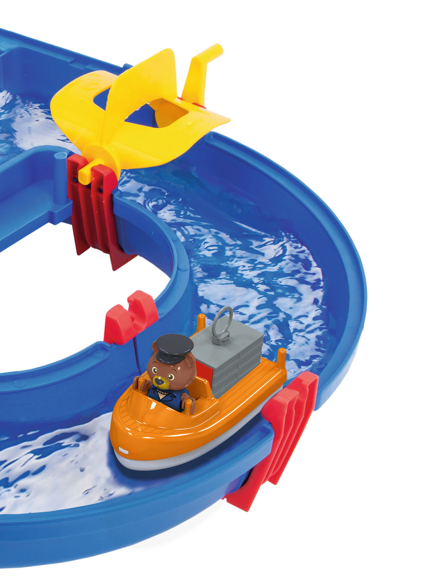 Ein Spielzeugboot mit Bärenkapitän fährt auf einer blauen Wasserbahn mit gelbem Propeller.