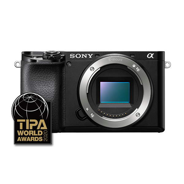 Fotocamera Sony nera con un obiettivo e un adesivo TIPA World Awards 2020. Su sfondo bianco.