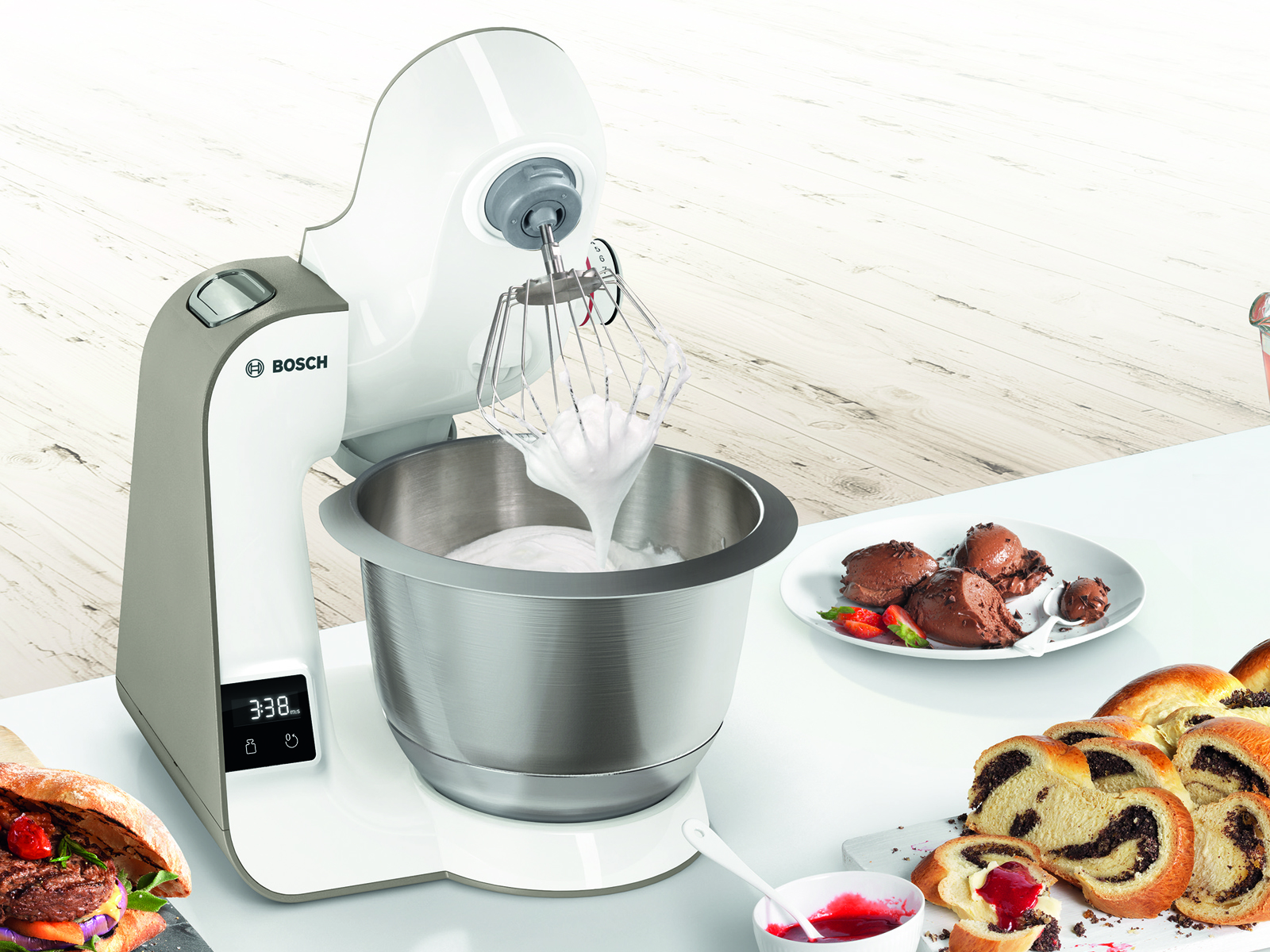 Een witte keukenmachine met een mengkom en ingrediënten als cake en aardbeien.