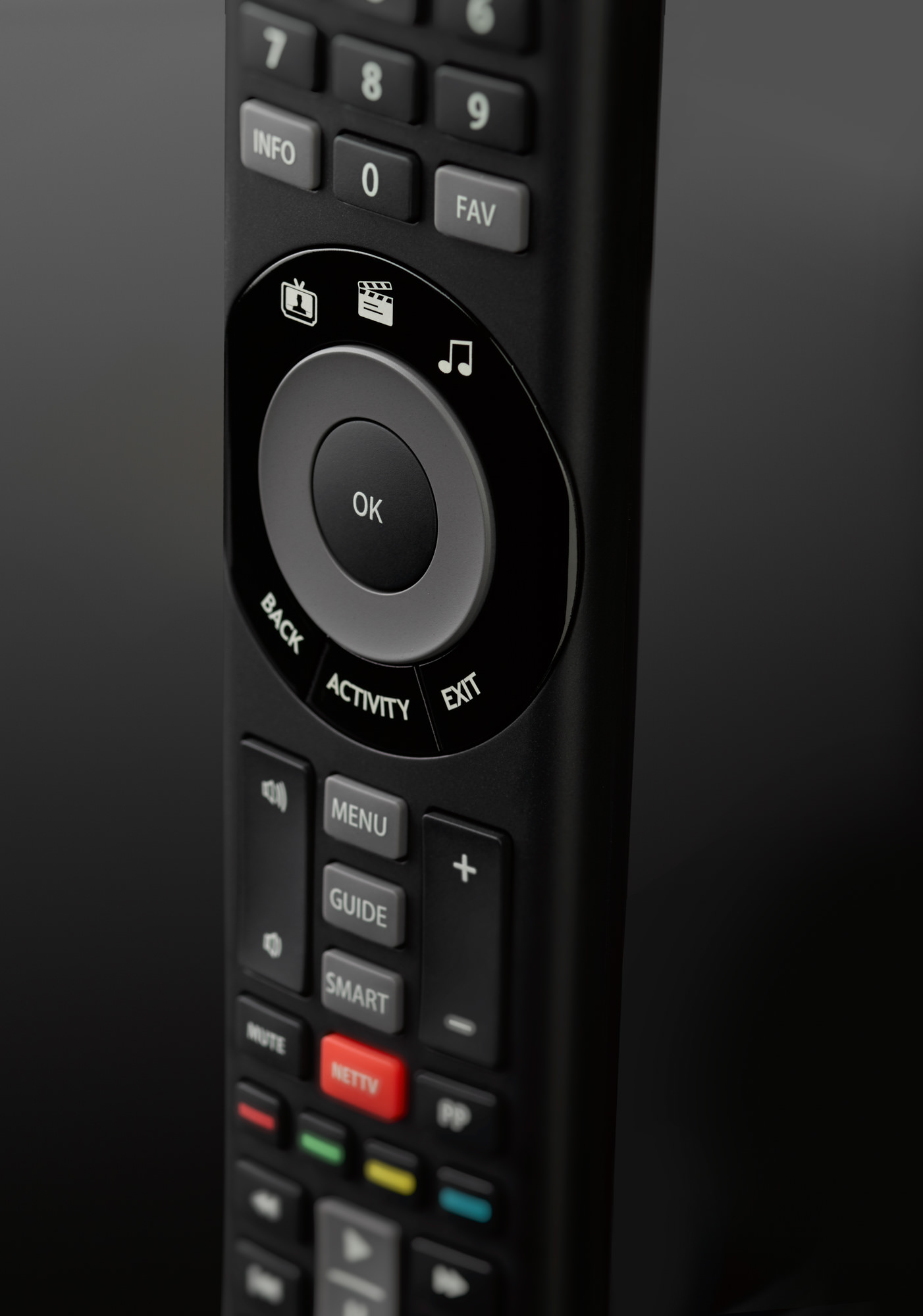 Nahaufnahme einer schwarzen Fernbedienung mit Tasten für TV, Filme, Musik, Menü und Lautstärke sowie einer zentralen OK-Taste.