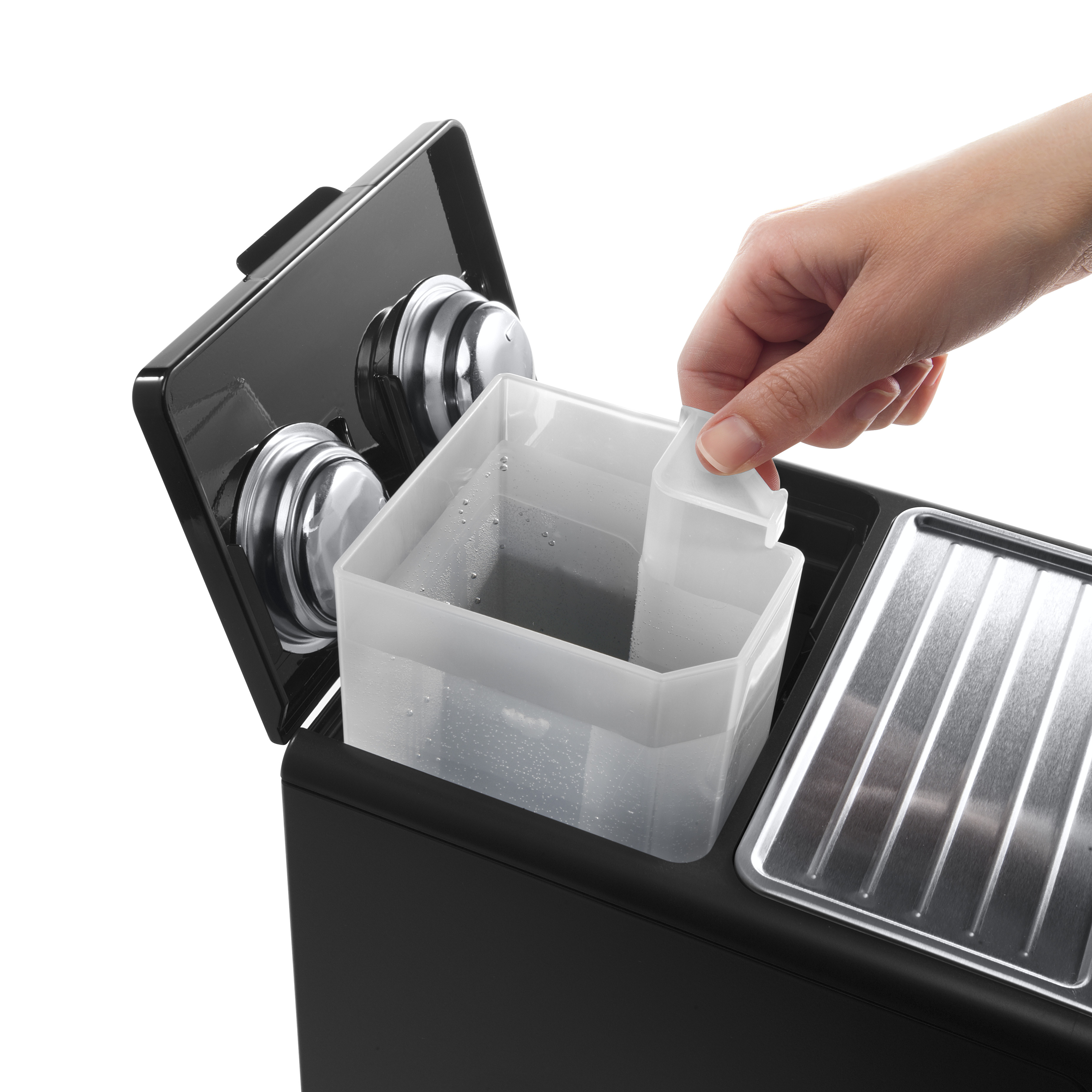 De hand van een persoon houdt een watertank van een zwart koffiezetapparaat vast.