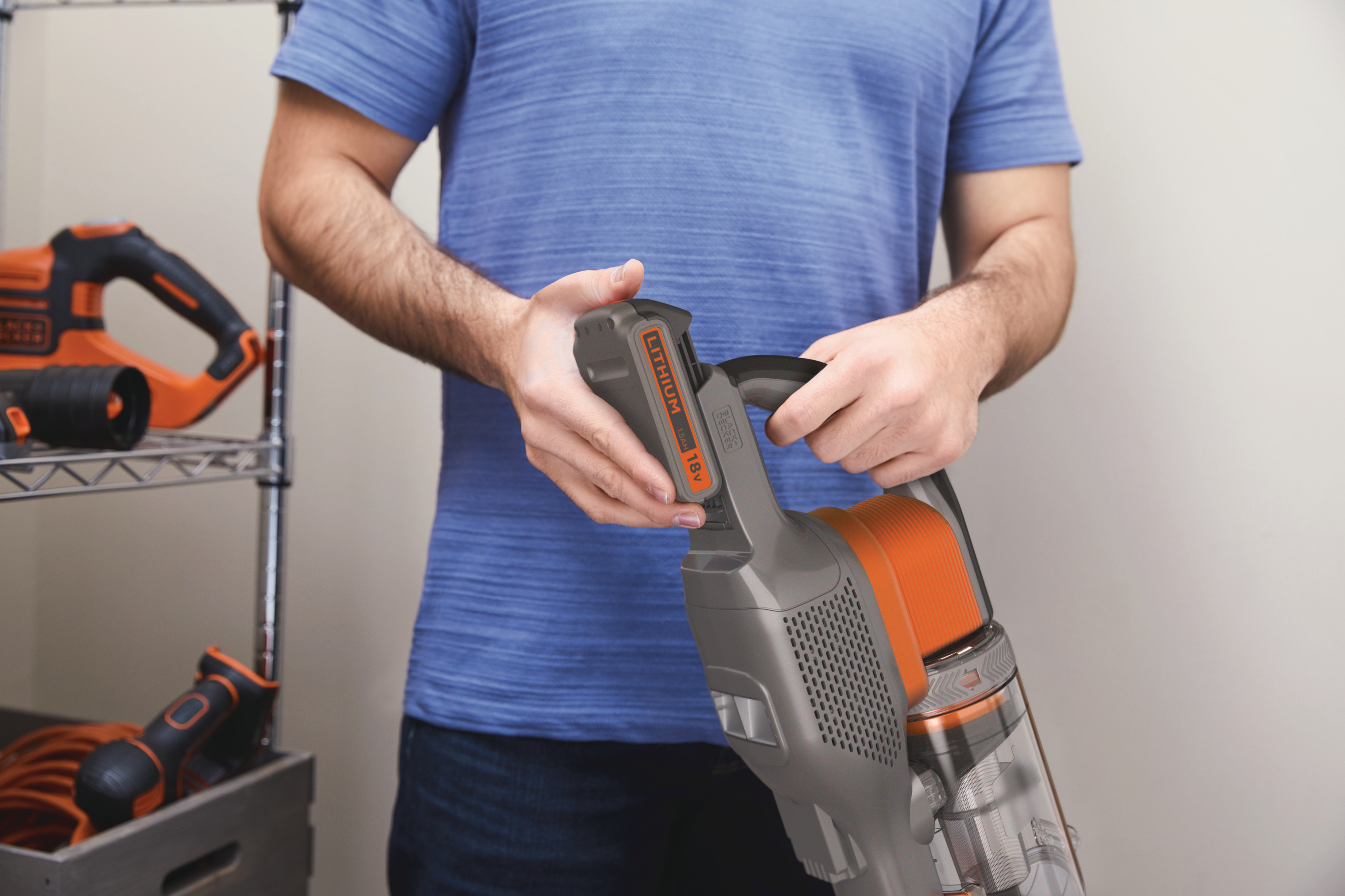Eine Person hält einen schnurlosen Staubsauger in Schwarz und Orange.