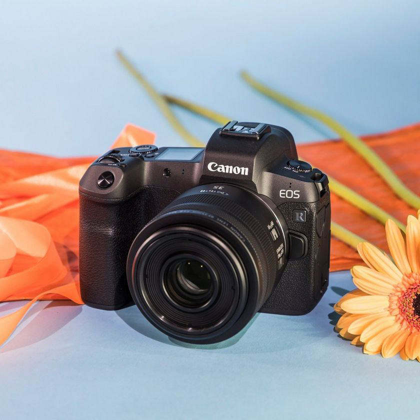 Schwarze Canon EOS Kamera mit Objektiv und Blume.