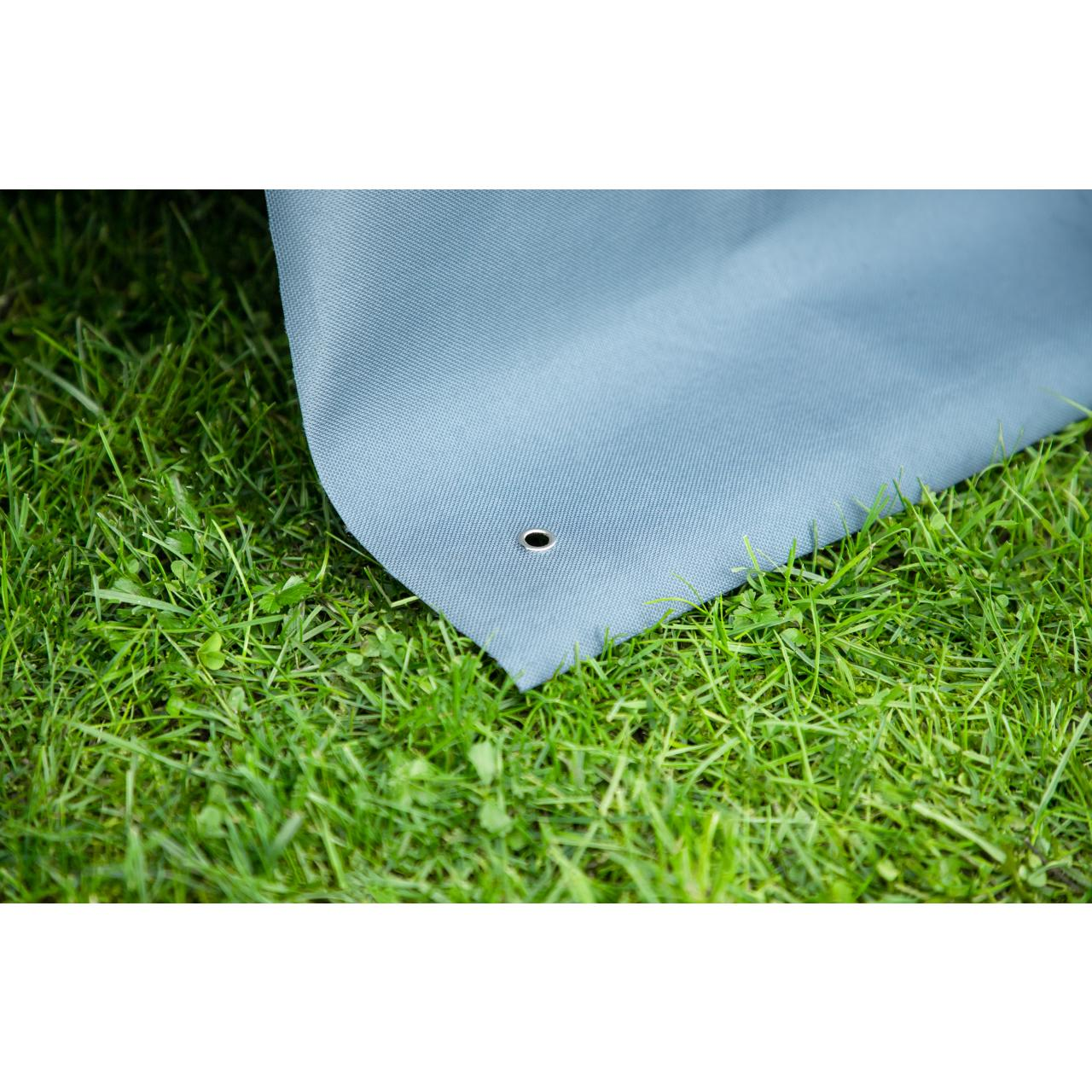 Eine Ecke einer blauen Plane über grünem Gras, mit einer Metallöse.