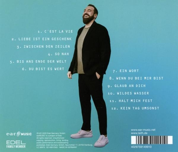 Ein Mann mit Bart steht vor blauem Hintergrund mit einer Liste von Songtiteln.