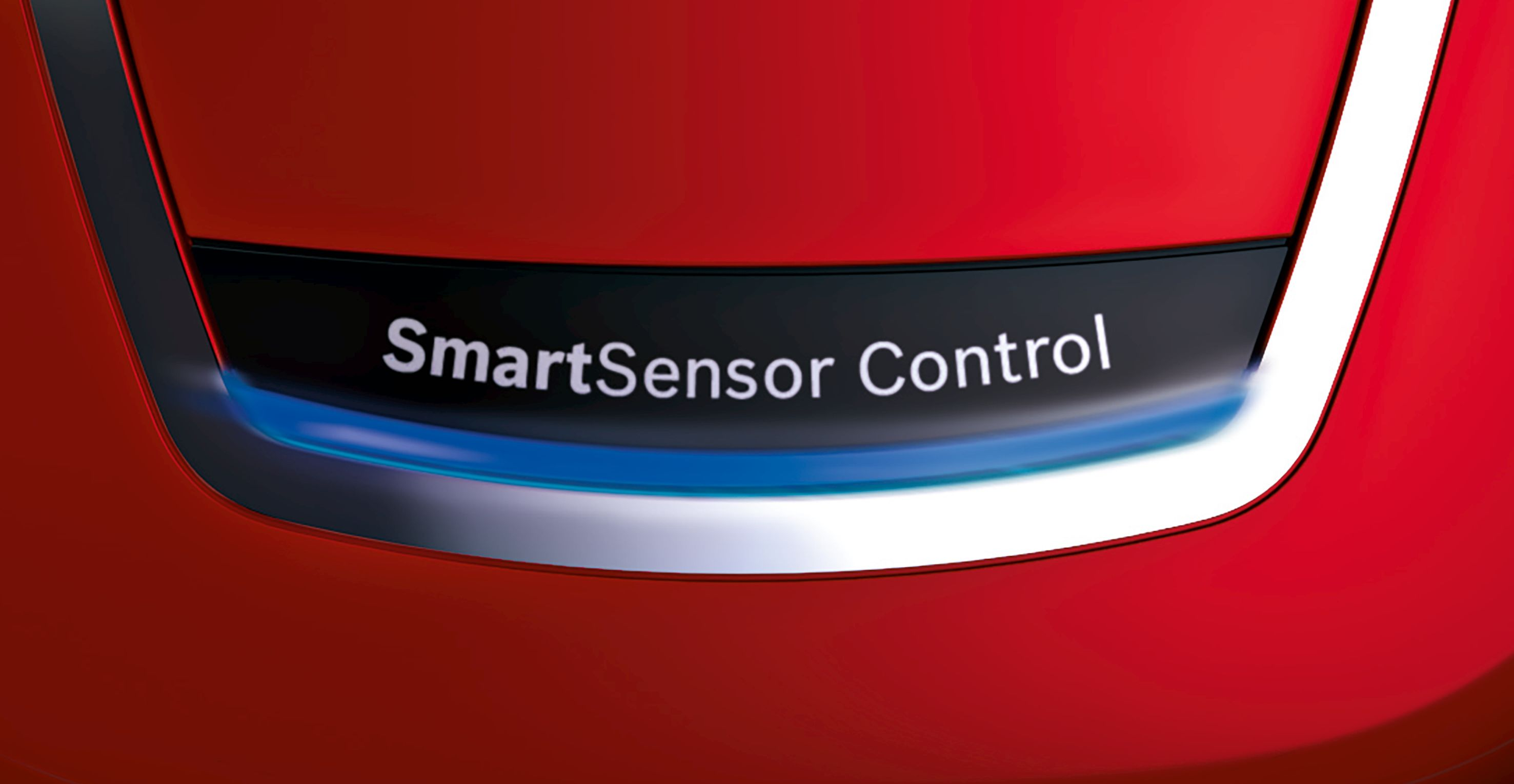 Piros felület 'SmartSensor Control' felirattal és ezüst szegéllyel. Közelkép, erős megvilágítás.