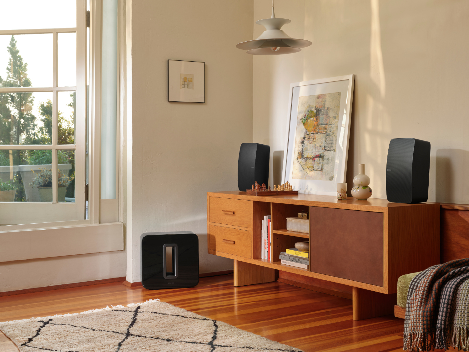 Living room with speakers, a wooden cabinet, and a window with natural light.