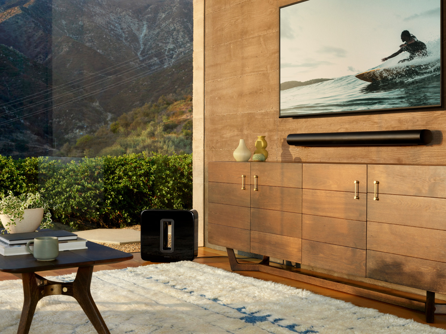 Een woonkamer met een houten kast, een tv, een surffoto en een zwarte soundbar.