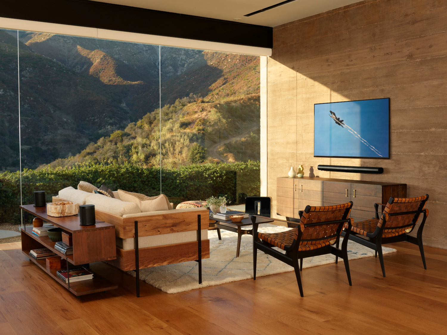 Woonkamer met tv, soundbar, bank en luidsprekers.
