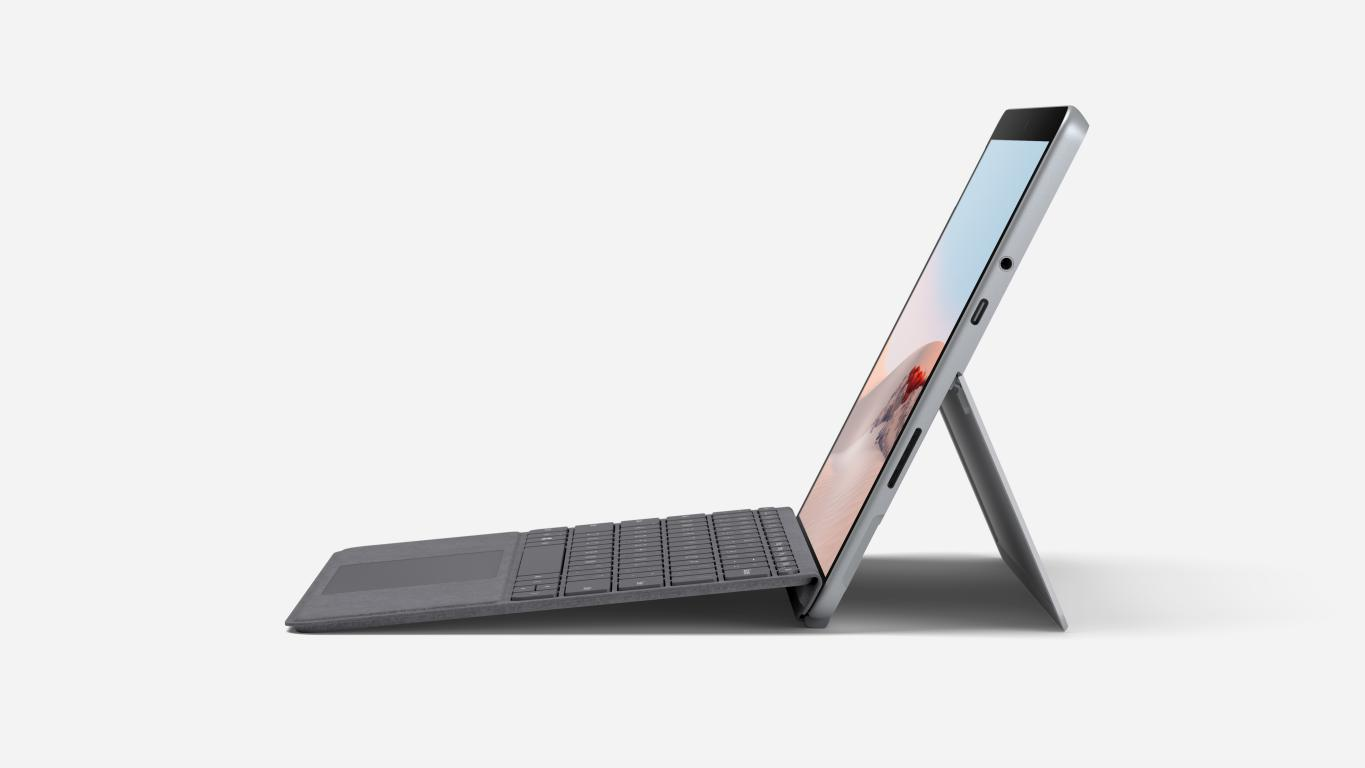 Una computadora portátil gris con un teclado rojo, abierta, sobre una superficie blanca.
