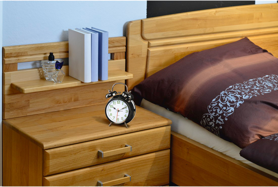 Ein Schlafzimmer mit Nachttisch, Bett und Uhr. Es hat eine blaue Wand.