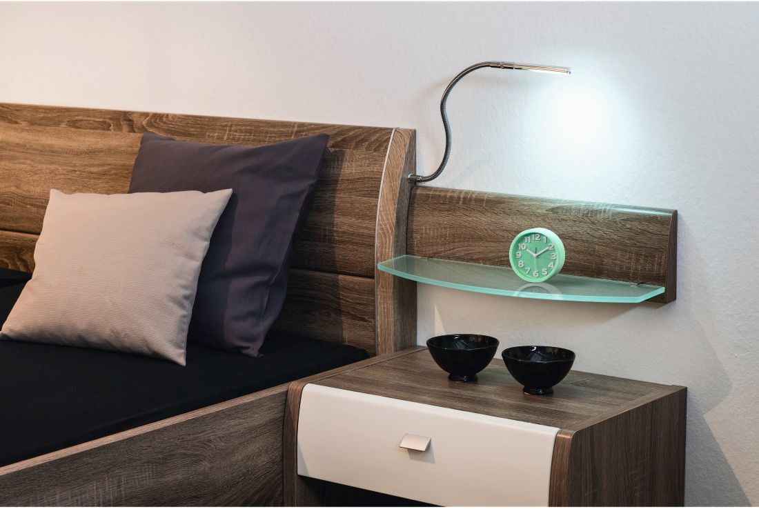 Table de chevet de chambre avec lampe, horloge et décoration.