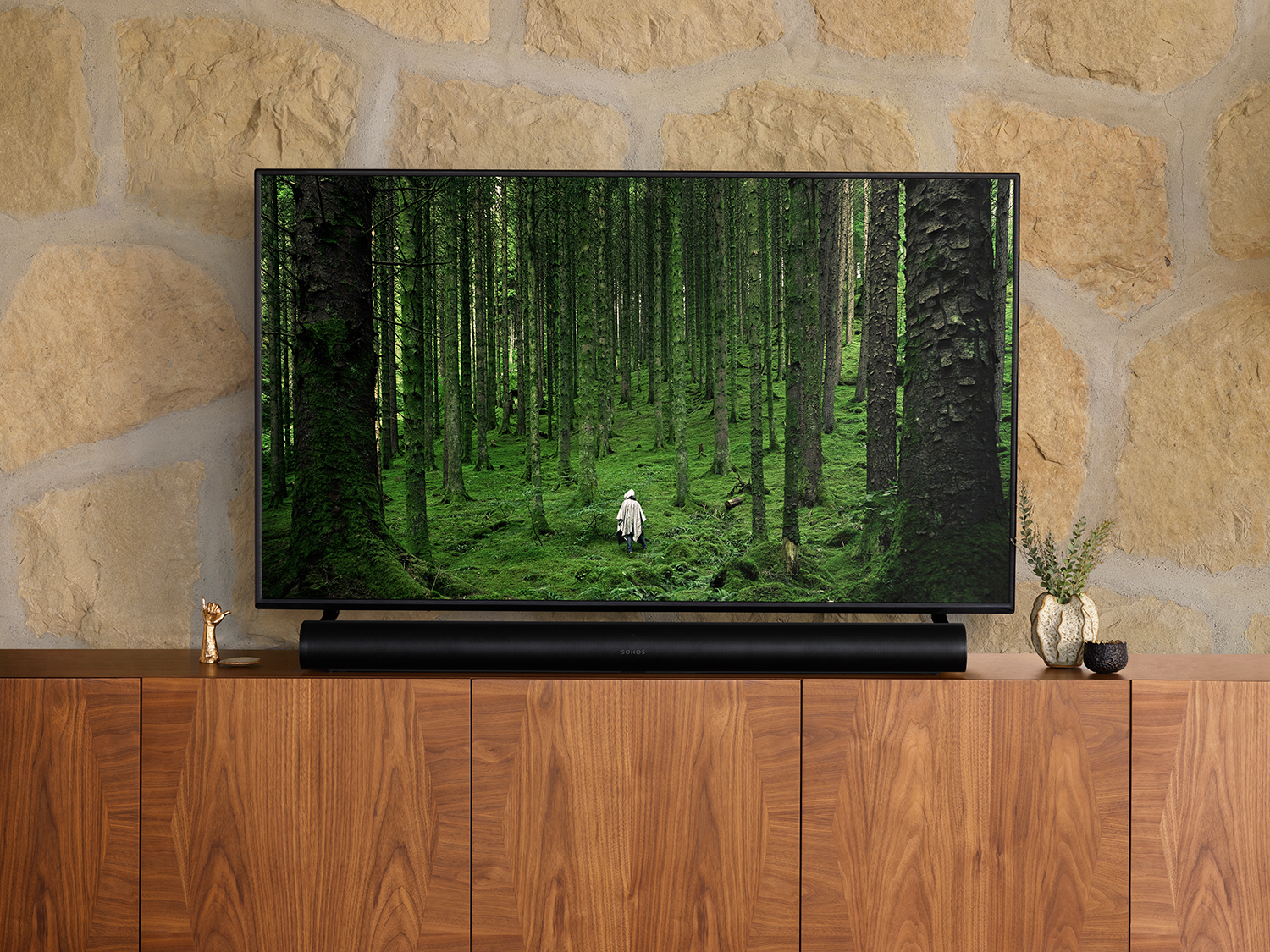 TV met bosscène. Soundbar, houten kast, stenen muur.