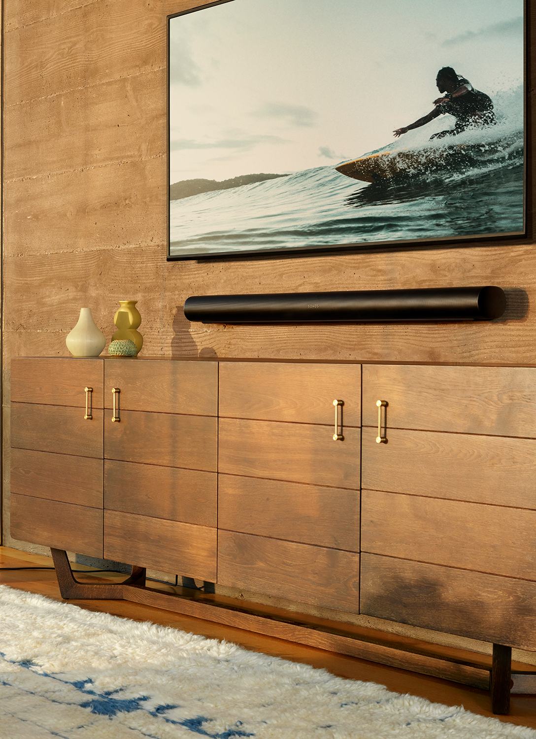 Woonkamer met een houten kast, tv en soundbar. Een foto van een surfer staat op de tv.