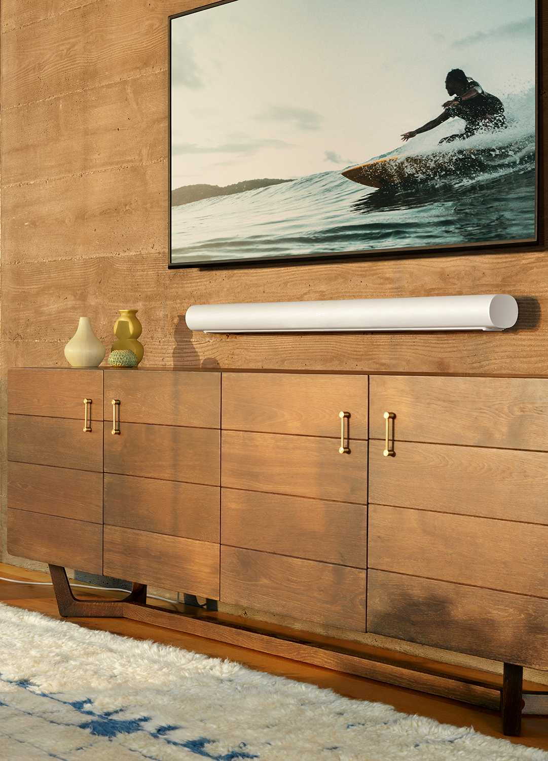 Een woonkamer met een tv, soundbar en een houten kast.