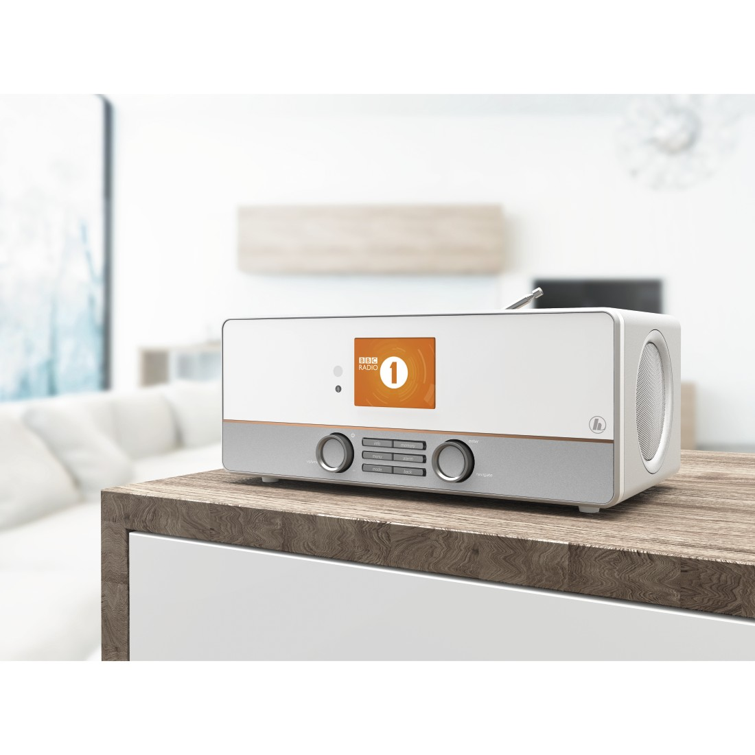 Weiß-silbernes Radio auf einem Holztisch. Es hat einen Bildschirm, der ein Logo anzeigt.
