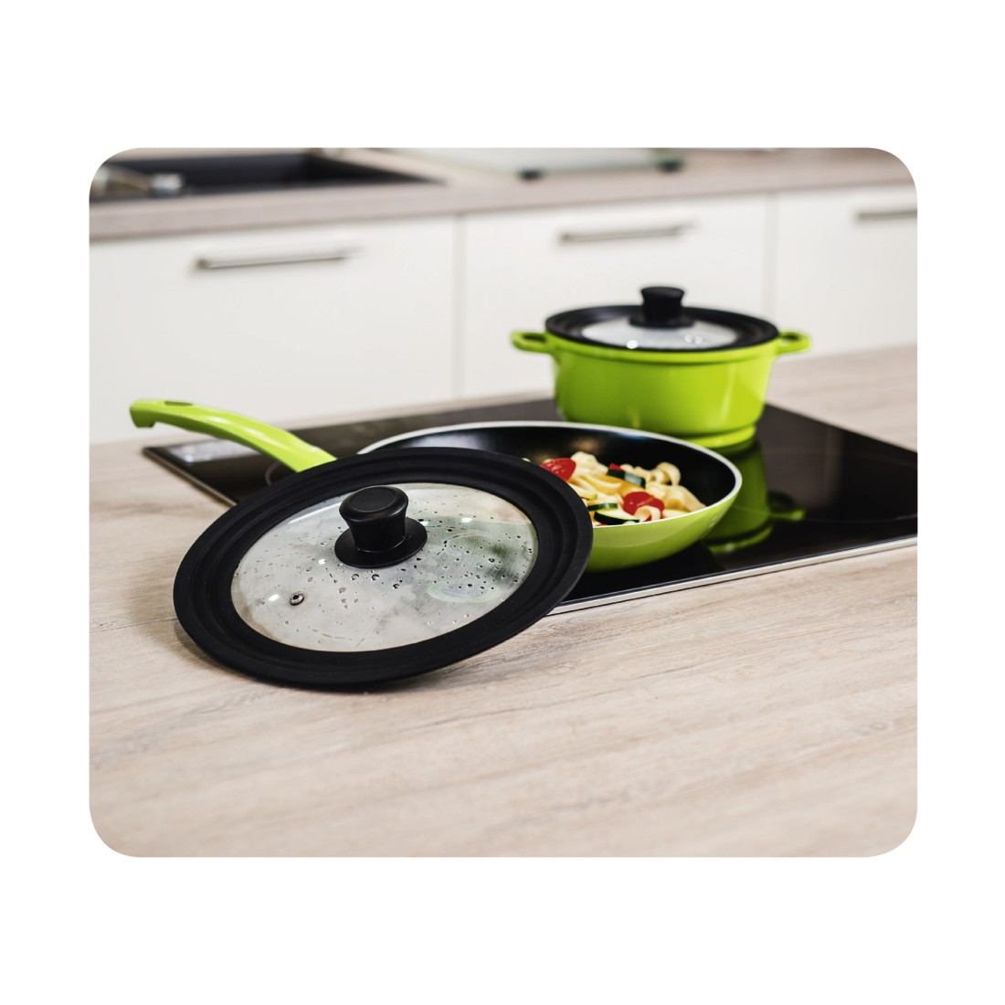 Grüne Bratpfanne mit Essen und ein Topf auf einem Herd mit Deckel.