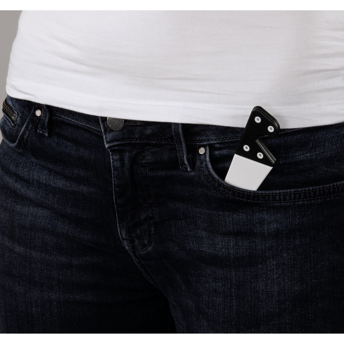 Die Hand einer Person mit schwarz-weißen Dominosteinen in der Hosentasche einer Jeans.