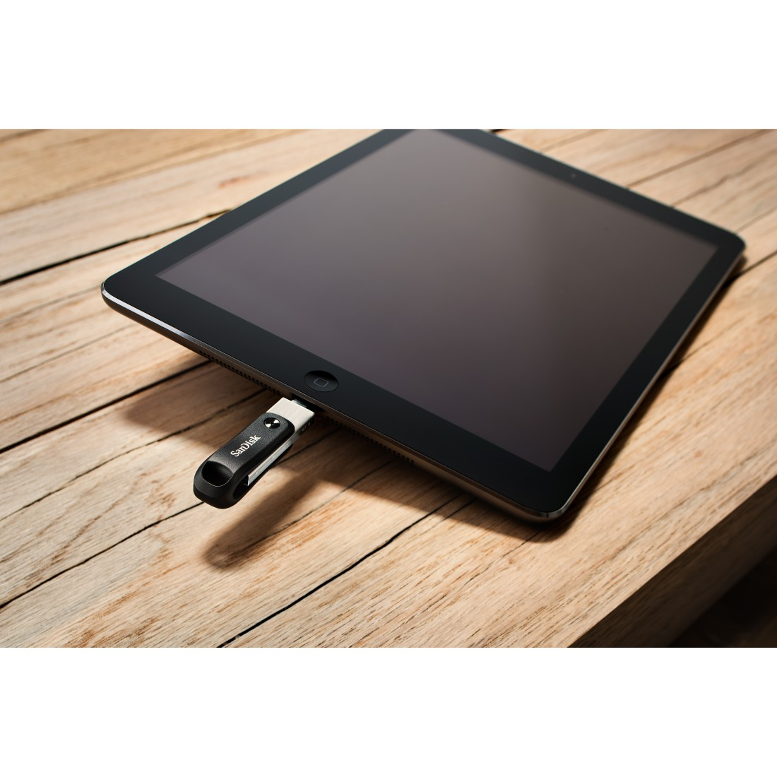 Ein schwarzes Tablet mit eingestecktem USB-Stick, auf einer Holzoberfläche. Der USB-Stick ist schwarz.