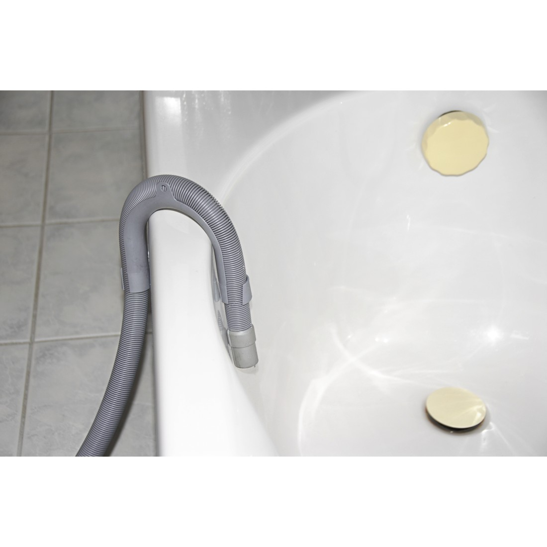 Weiße Badewanne mit grauem Wellschlauch und zwei goldenen runden Abdeckungen.
