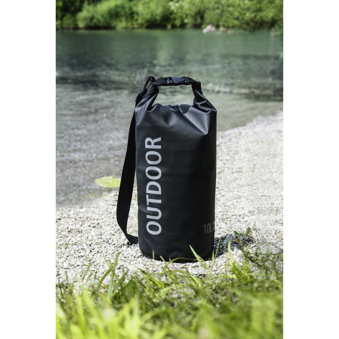 Schwarzer wasserdichter Beutel mit „OUTDOOR“-Aufschrift am Ufer.