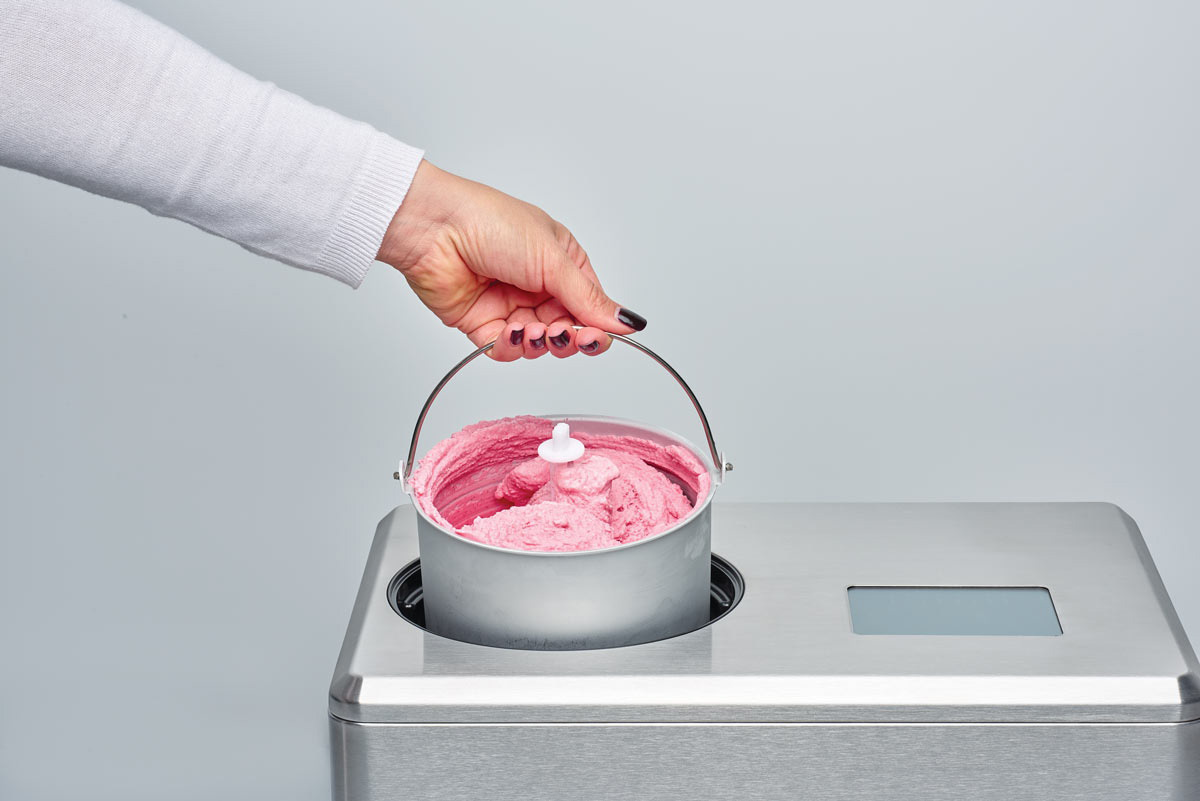 Une personne tenant une machine à crème glacée avec de la crème glacée rose.