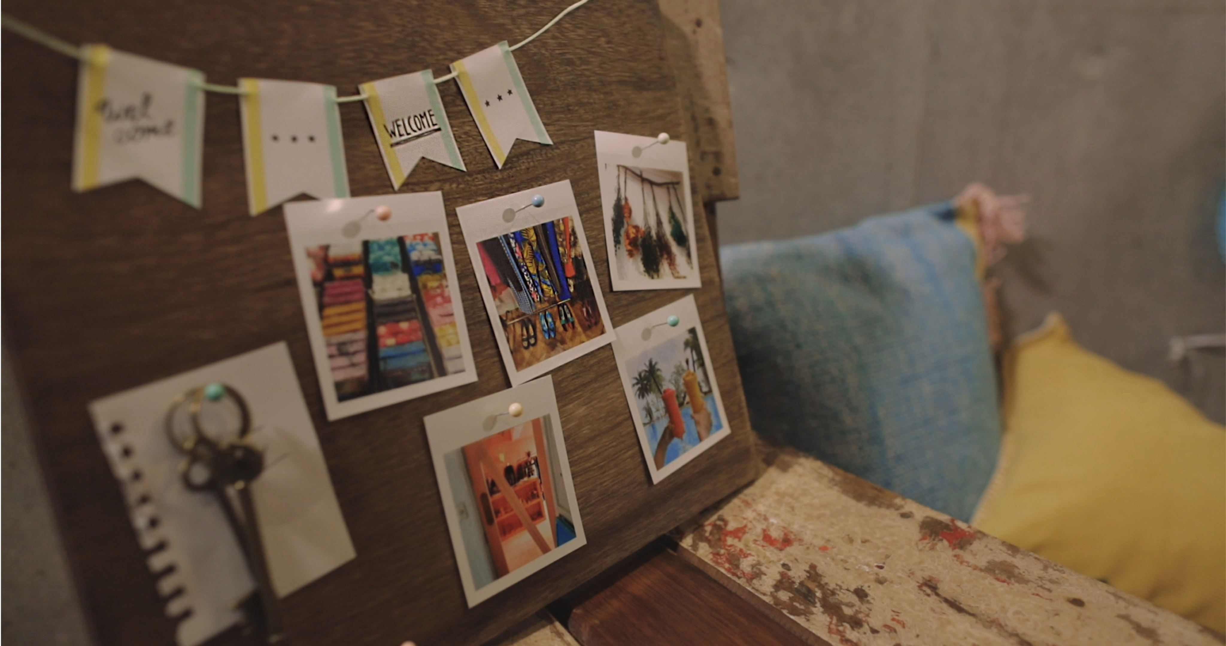 Holzbrett mit Fotos im Polaroid-Stil, die daran befestigt sind. Willkommensbanner oben.