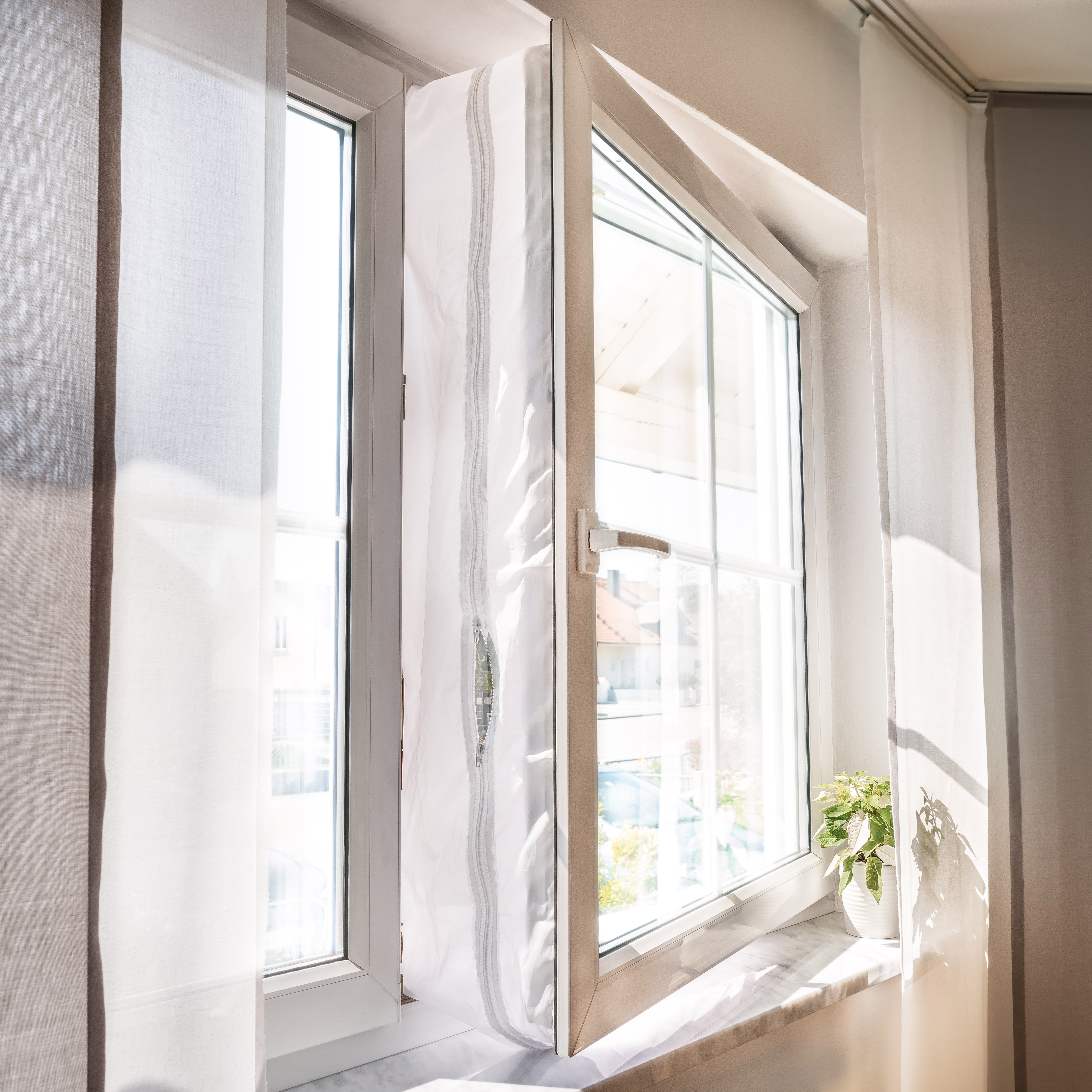 Fenster mit weißem Rahmen, geöffnet mit hellem Ausblick, mit transparenten Gardinen.