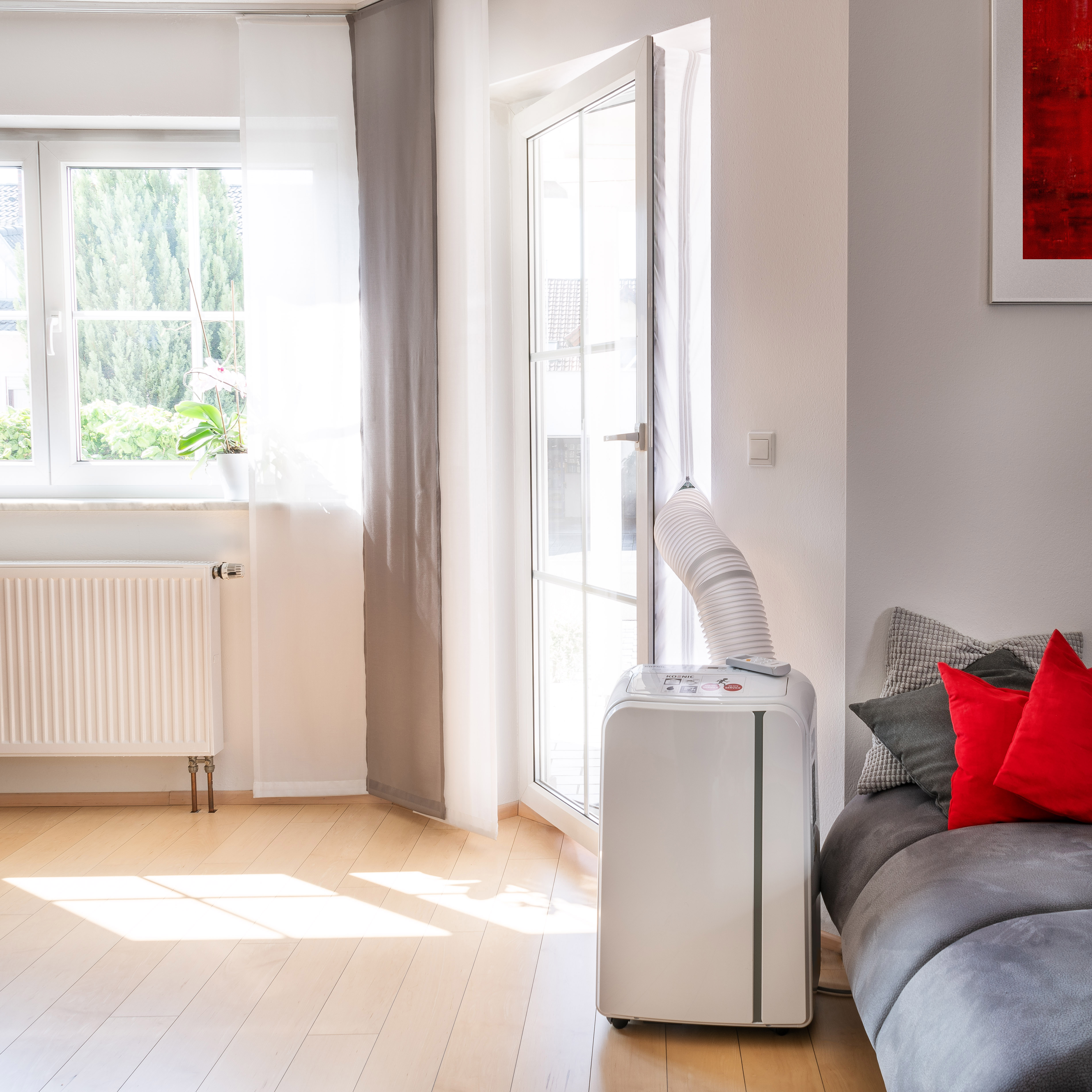 Ein Raum mit einem Luftkühler neben einem Fenster. Rechts ist ein Sofa.