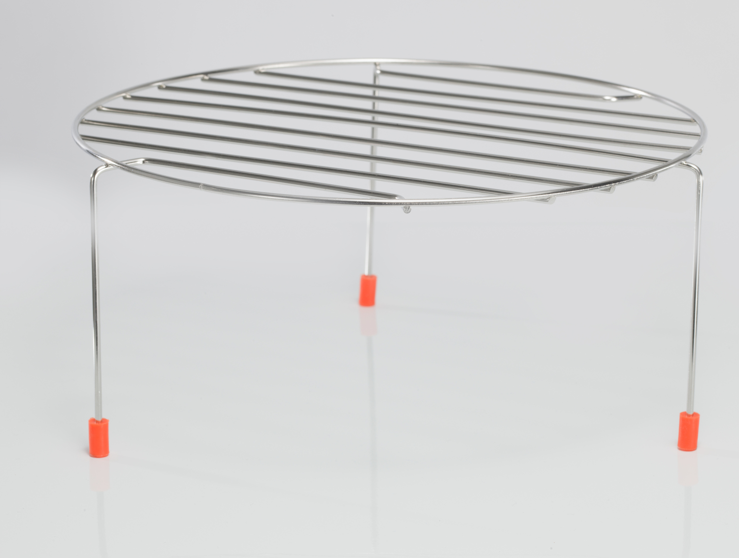 A chrome wire rack with three legs, each tipped with an orange rubber foot. The rack is on a white surface.