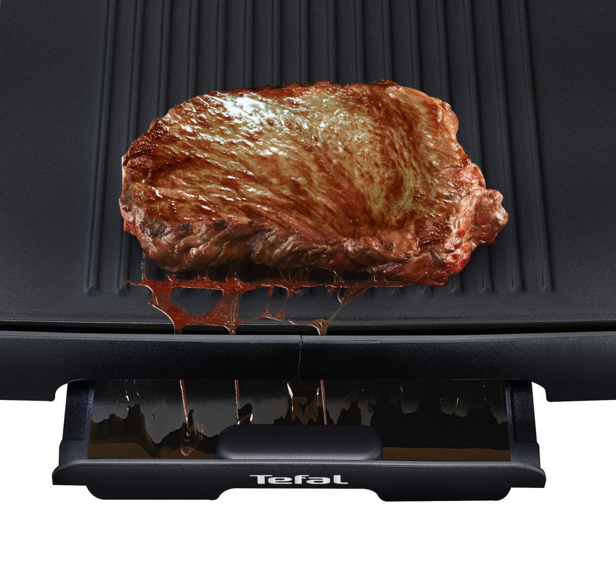 Ein gebratenes Steak auf einem schwarzen Grill mit Tropfschale. Saftig.