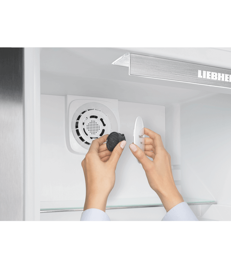 Hands removing a filter from a fridge.