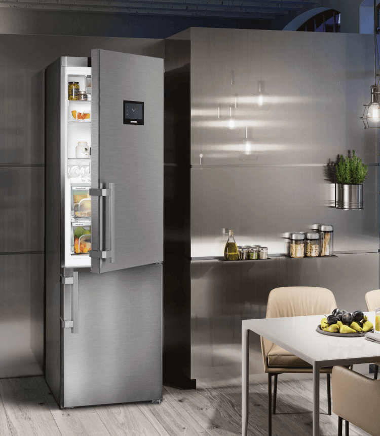 A stainless steel fridge with an open door in a modern kitchen setting.
