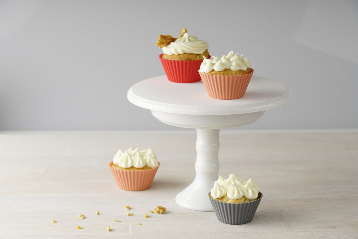 Vier Cupcakes auf einem weißen Kuchenständer. Die Cupcakes sind in verschiedenen Haltern.