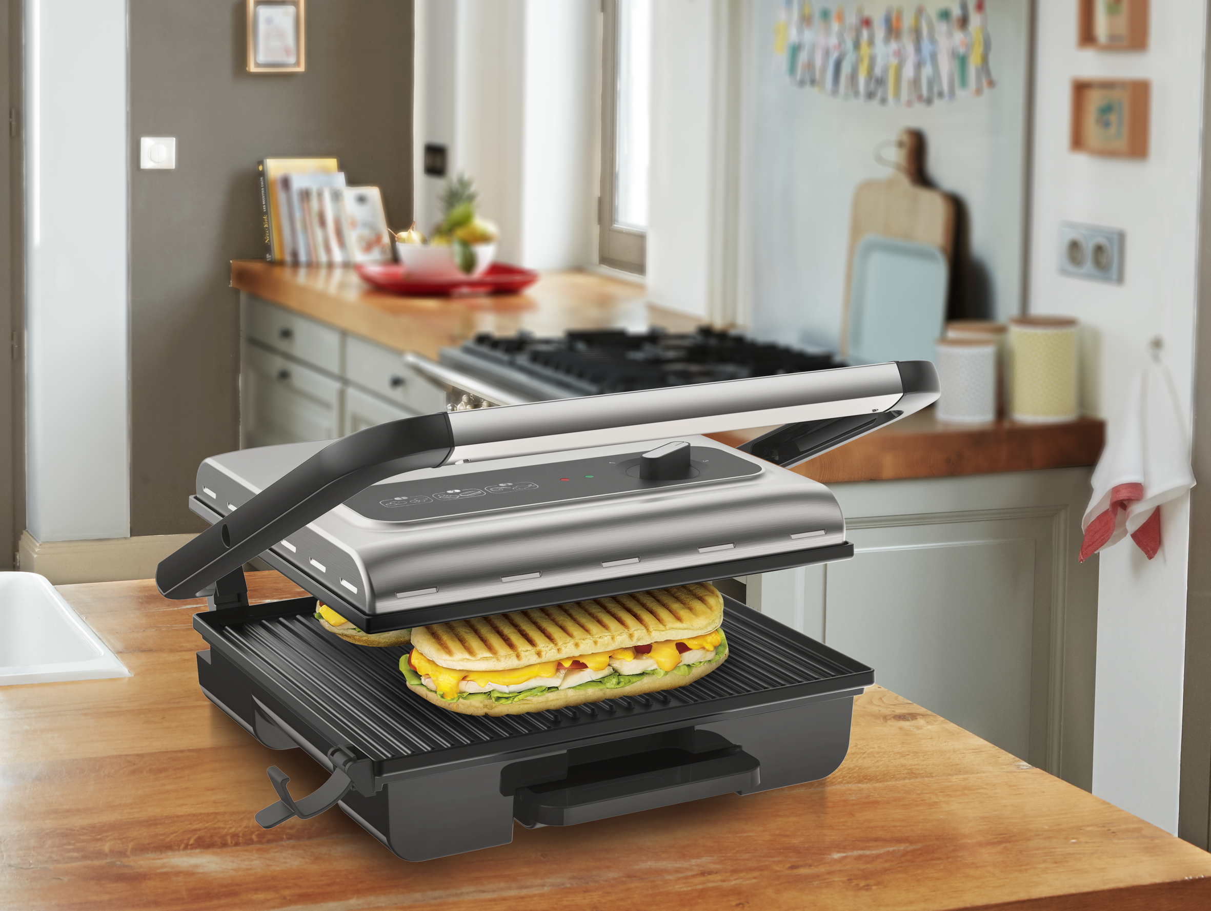 Presse à panini argentée avec sandwich, sur comptoir bois dans une cuisine.