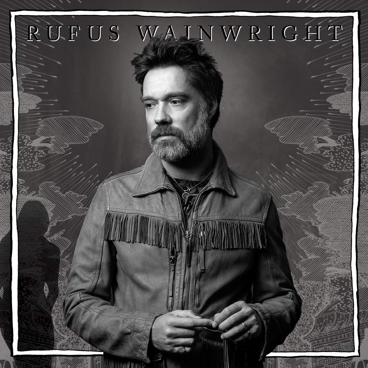 Fekete-fehér fotó Rufus Wainwrightról. Rojtos dzsekit visel, balra néz. A háttérben grafikus dizájnok láthatók.