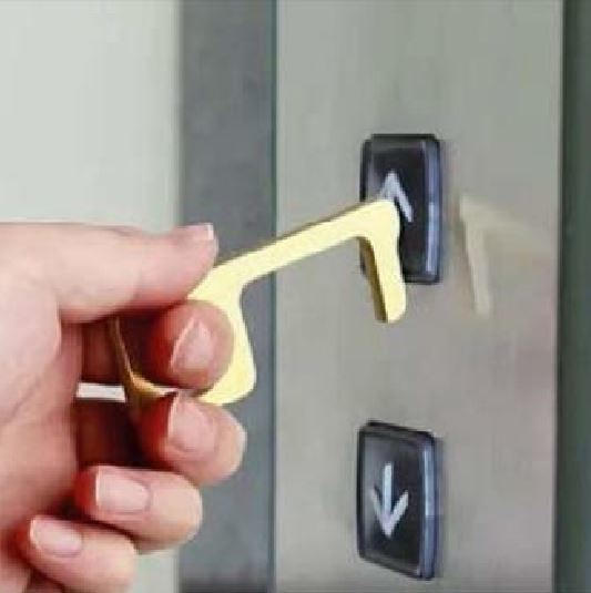 Une main tient un outil doré pour appuyer sur un bouton d'ascenseur. Les boutons d'ascenseur sont noirs.