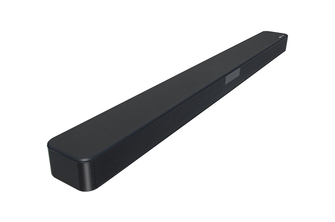 Una barra de sonido negra con una parte frontal de malla. Es rectangular, horizontal sobre una superficie blanca.