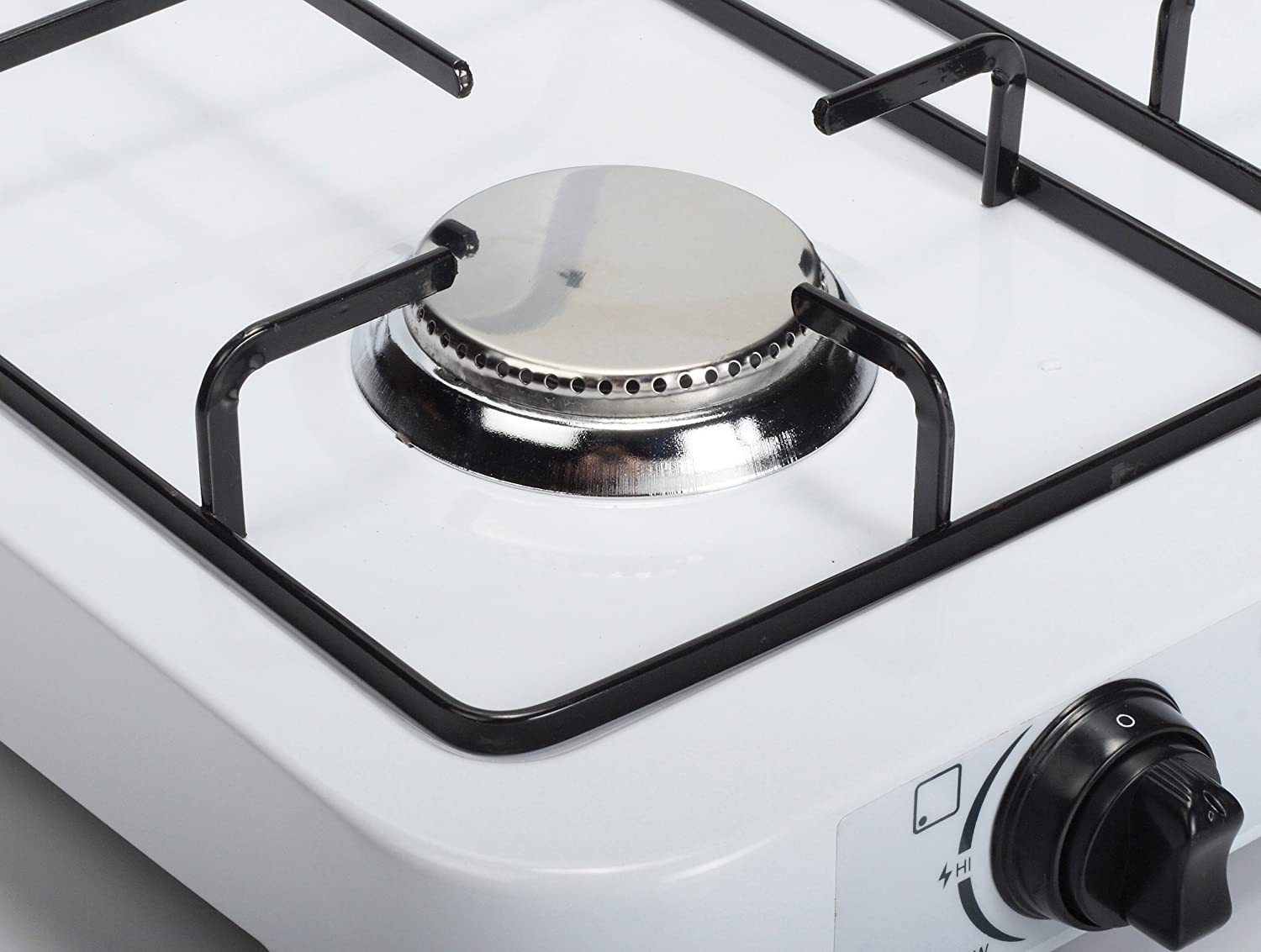 Close up of a white gas stove top, with black grates and a burner.