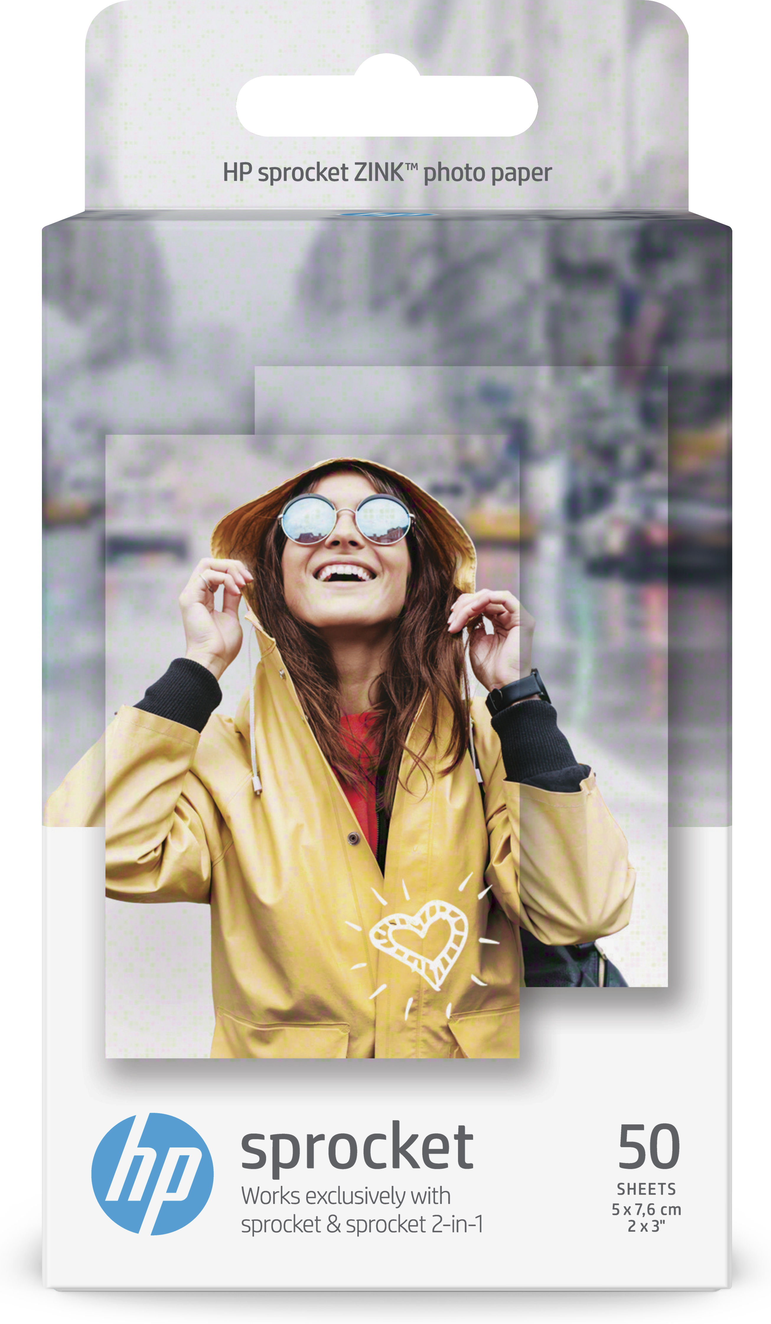 Eine Frau in einem gelben Regenmantel hält ein Foto aus einer Packung HP Sprocket Fotopapier hoch.