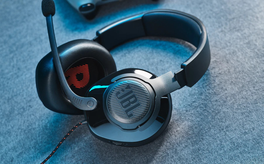 Black JBL gaming headset with a microphone. The headset is on a blue textured surface.