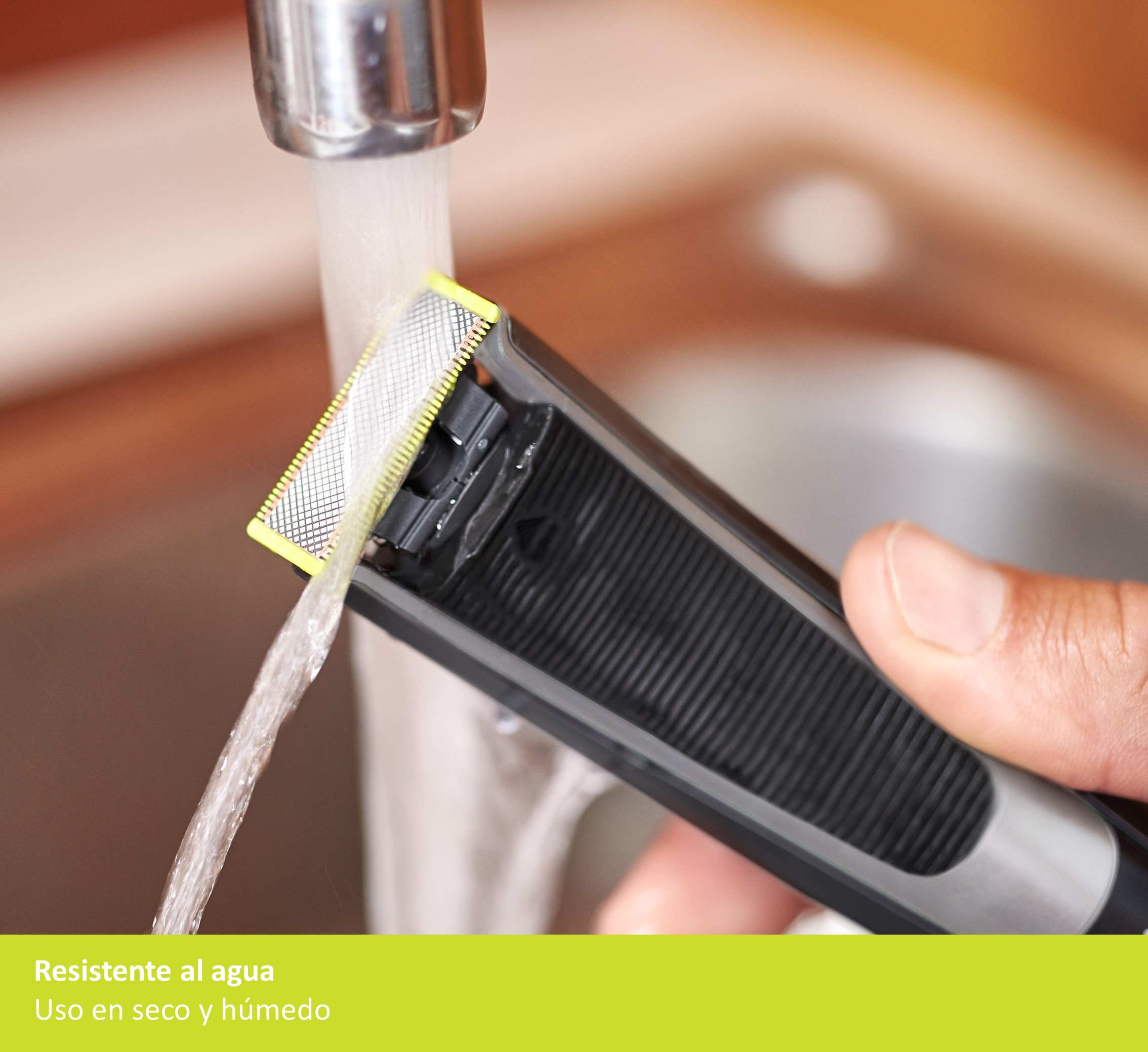 Una afeitadora se enjuaga bajo agua corriente, con un protector de cuchilla amarillo y negro.