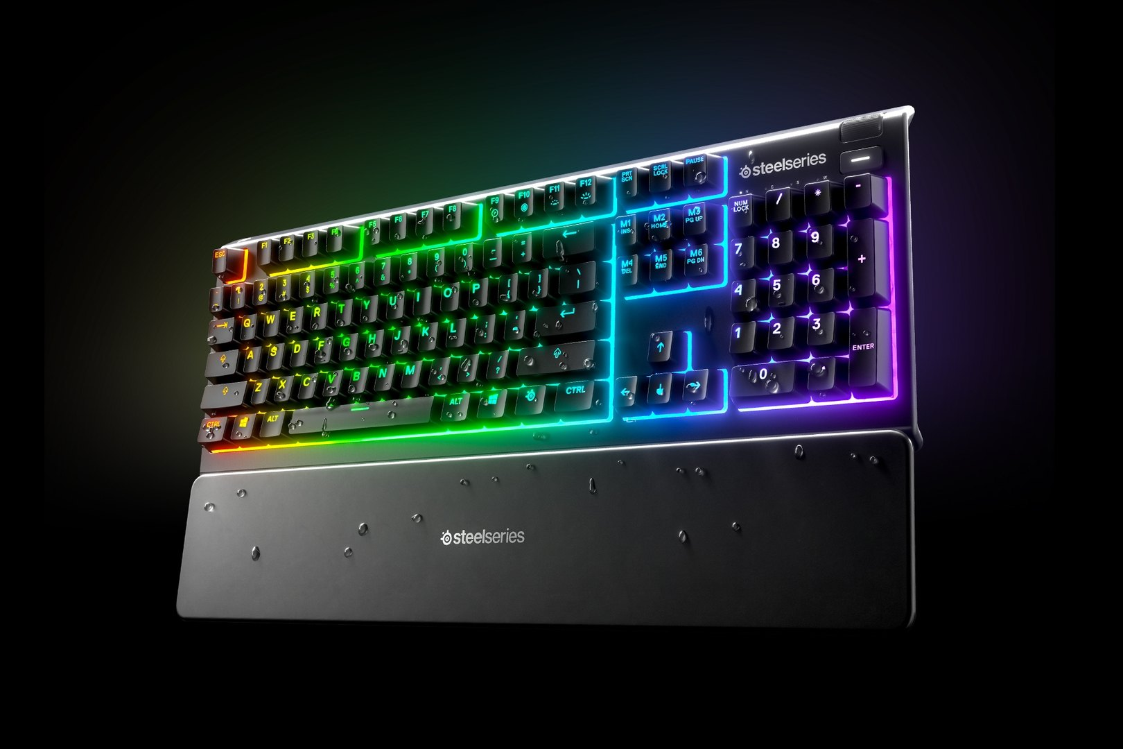 Fekete SteelSeries billentyűzet többszínű világítással. Csuklótámasza és vízcseppek vannak rajta.