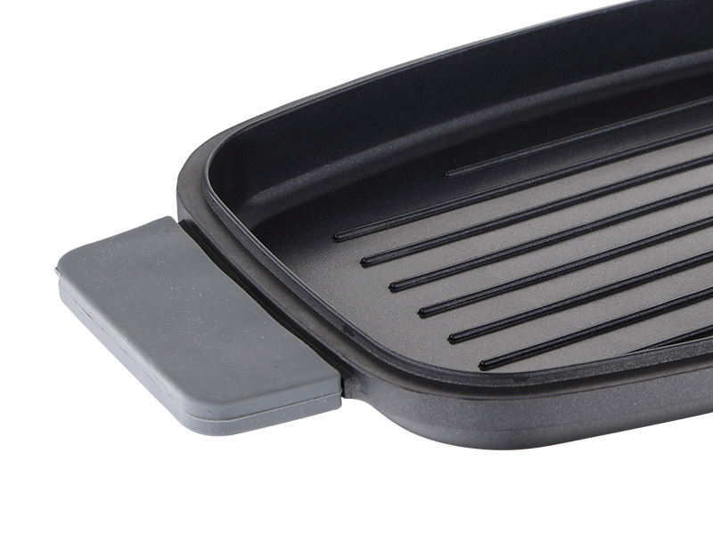 Egy fekete grill serpenyő közelről, szürke fogantyúval.